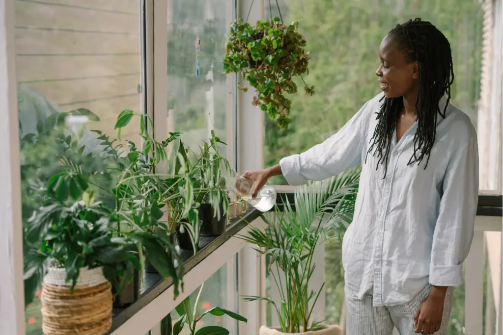 person watering their plants, with a huge smile on their face